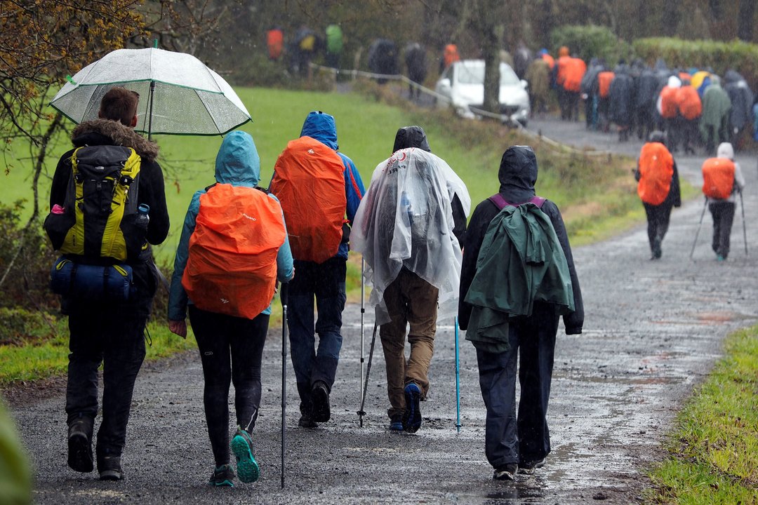 Un grupo de peregrinos camina bajo la lluvia a su paso por el municipio lucense de Palas de Rei.