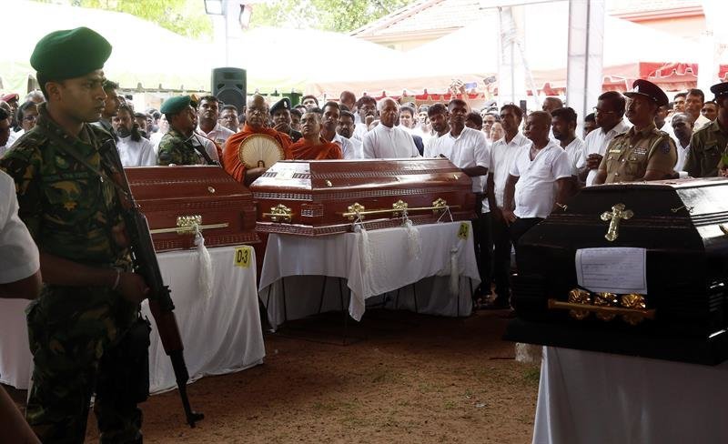 Un soldado monta guardia mientras familiares y amigos asisten al funeral de varias de las víctimas