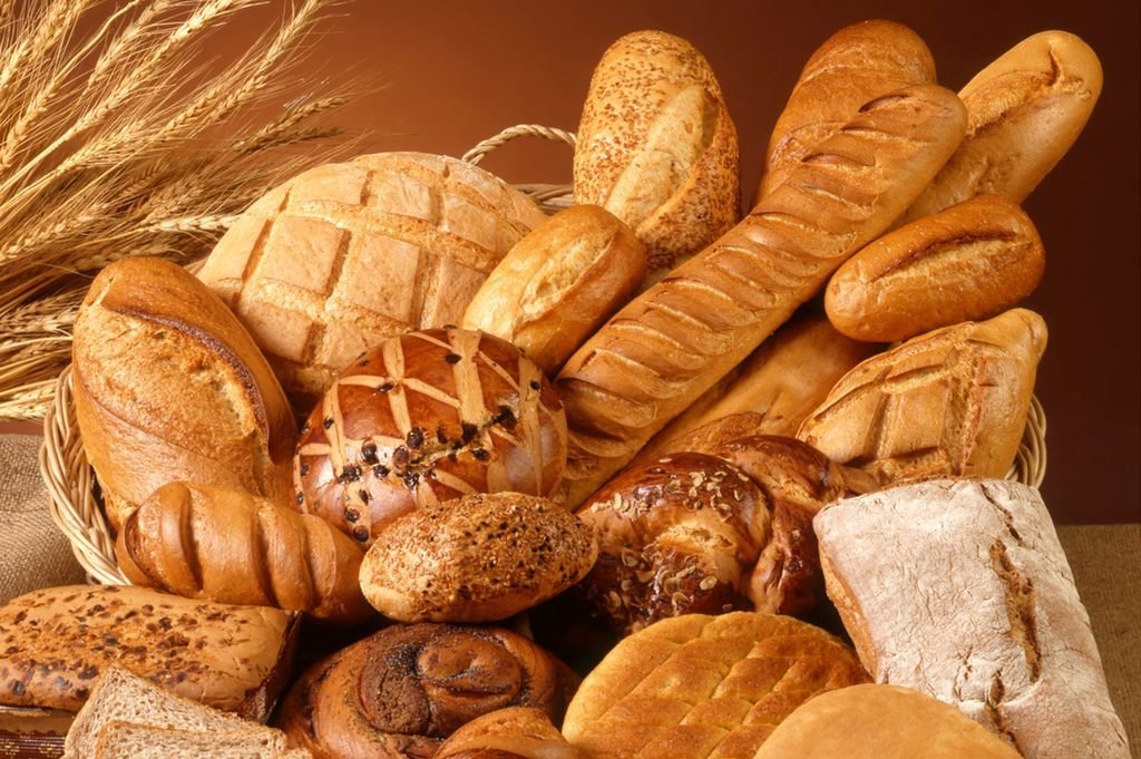 Varias piezas de pan de diferentes estilos, posados sobre una cesta.
