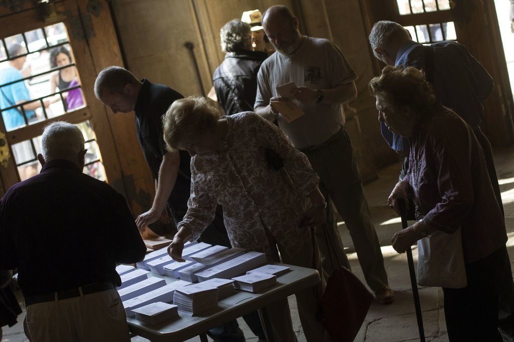 Un grupo de ciudadanos elige sus papeletas en un colegio electoral.