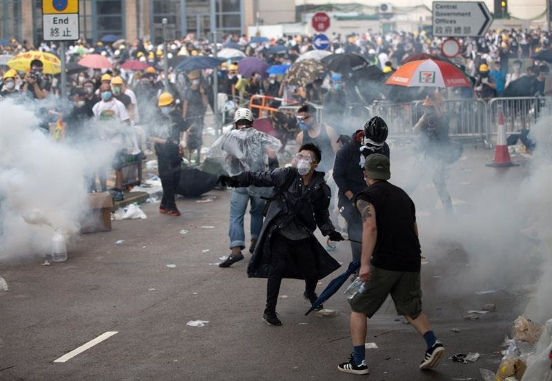 Un manifestante lanza de vuelta una lata de gas lacrimógeno a la policía durante las protestas