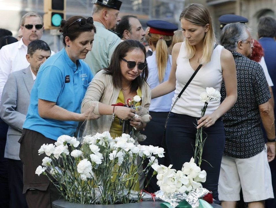 Familiares de las víctimas y afectados depositan claveles blancos durante el acto en las Ramblas.