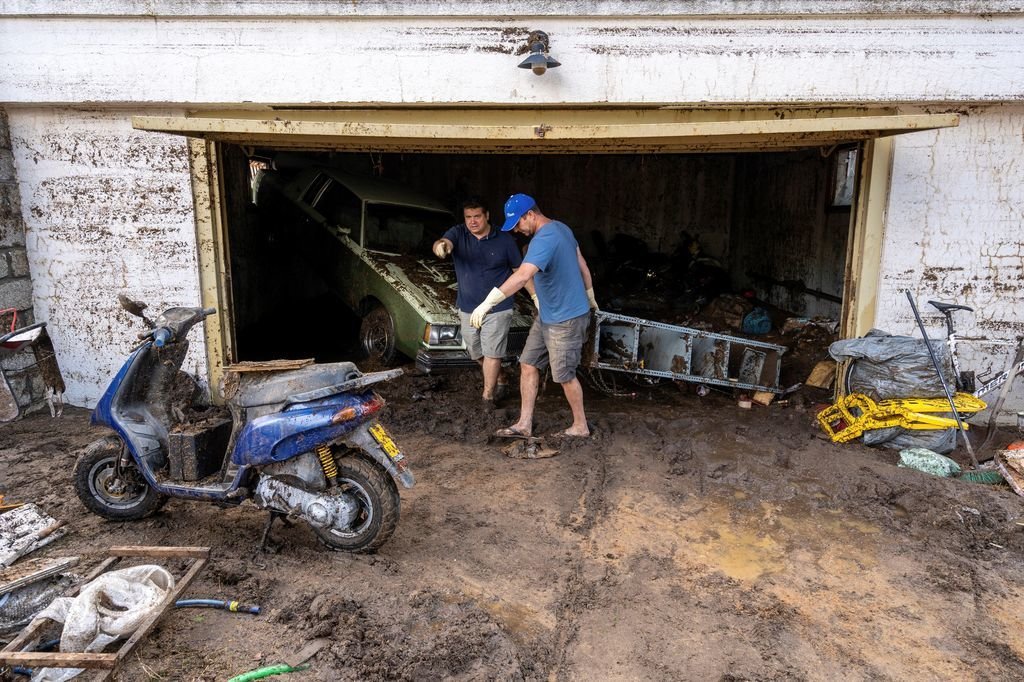 Dos hombres quitan enseres para limpiar un garaje en la Colonia Botella de Las Navas del Marqués.