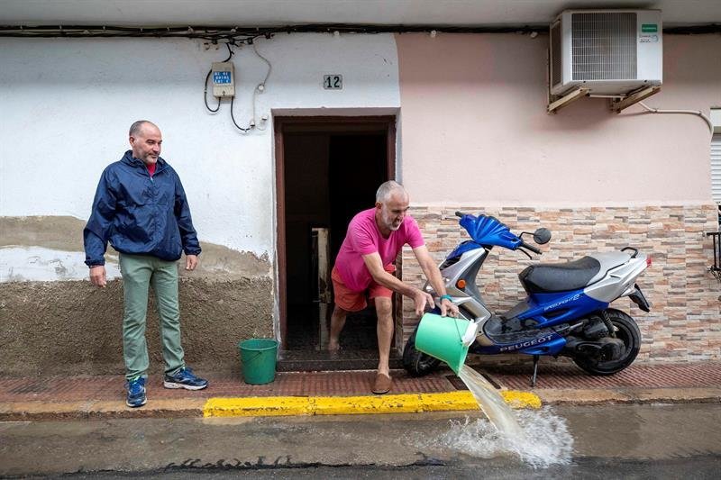 Un hombre achica el agua que ha inundado su vivienda del barrio de las casas baratas de Blanca, Murci