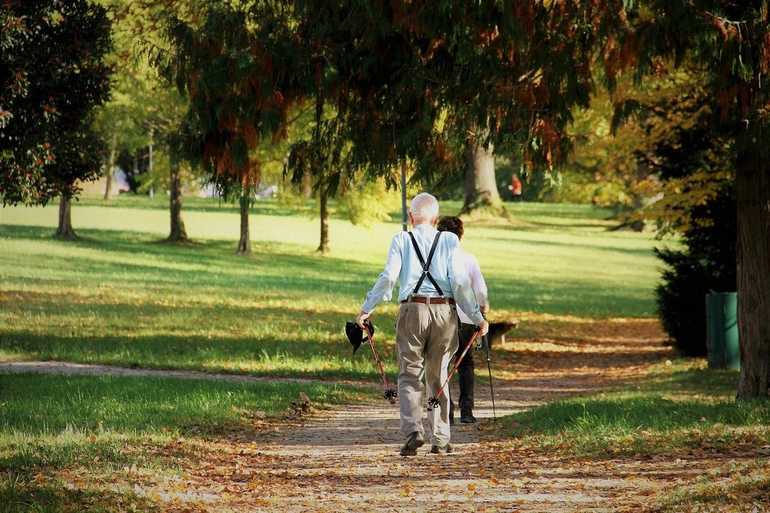Dos personas mayores dan un paseo por un parque.