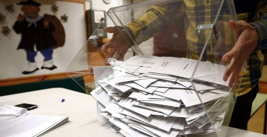 El miembro de una mesa electoral traslada una urna con papeletas.