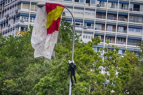 Un paracaidista que descendía con la bandera de España se ha quedado enganchado de una farola en el desfile del Día de la Fiesta Nacional, en Madrid