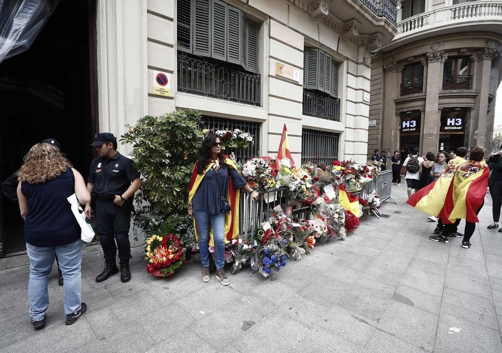 Ramos de flores y banderas de España depositados ante la Prefectura de la Policía Nacional en Barcelona.