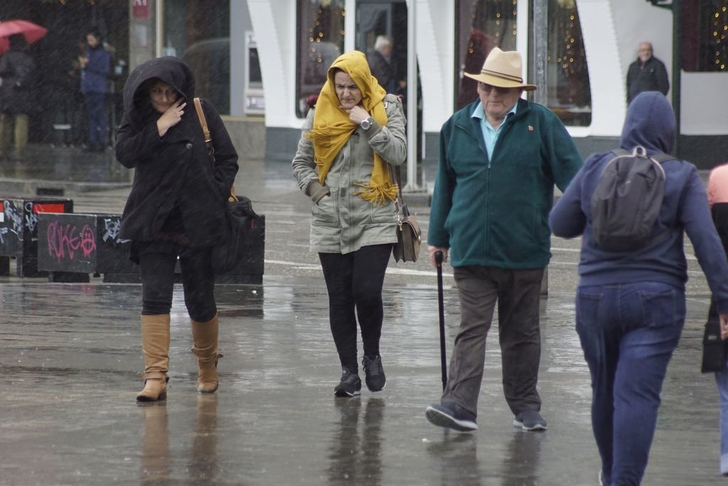 Turistas bajo la lluvia en el entorno del puerto, ayer.