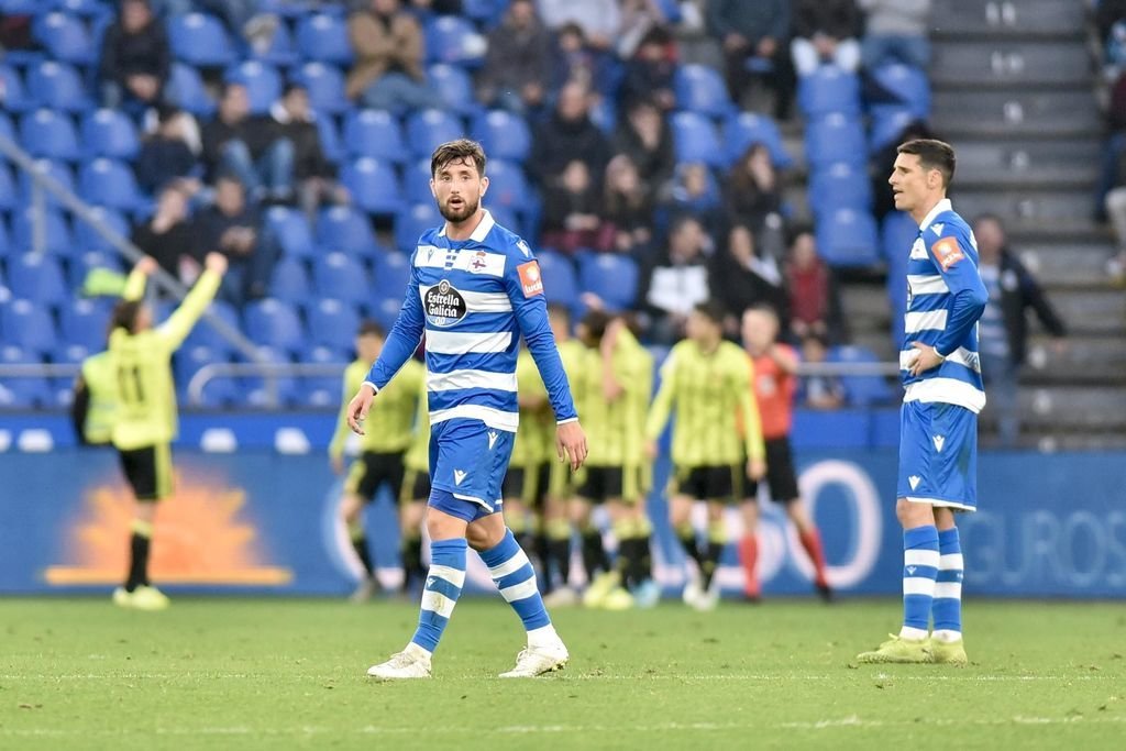 Borja Valle y Vicente Gómez, cariacontecidos, mientras el Zaragoza celebra al fondo uno de sus goles.