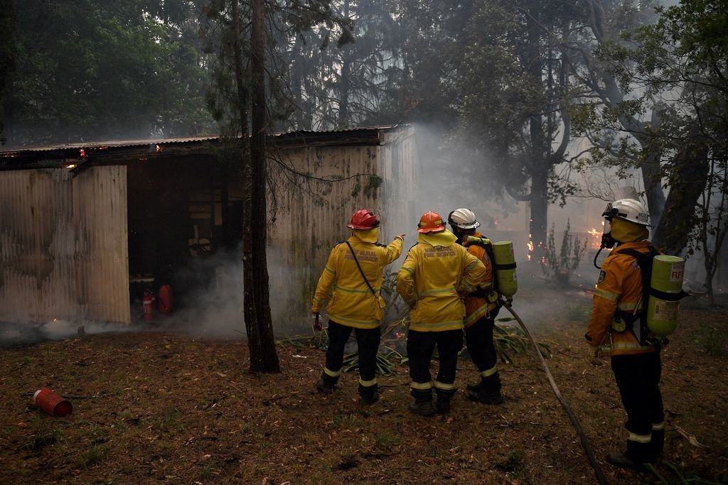 Un grupo de bomberos trata de impedir que el fuego arrase unas casas en Blue Mountains.