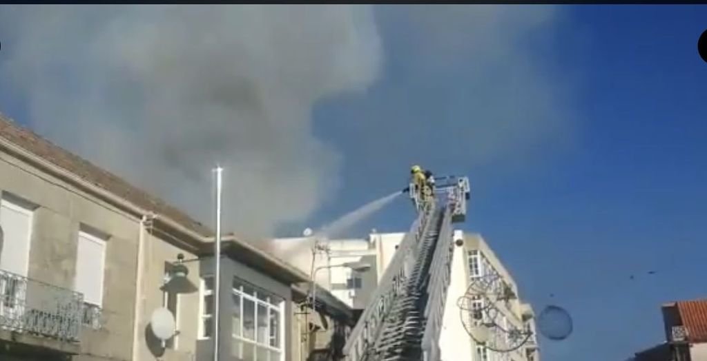 Los bomberos, sofocando el fuego, en el tejado de la casa.