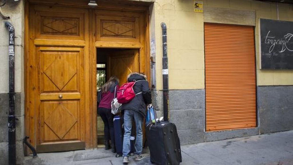 Una pareja accede al portal de un edificio de pisos turísticos.