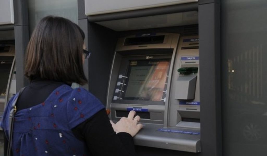 Una joven utiliza un cajero automático de una oficina bancaria.