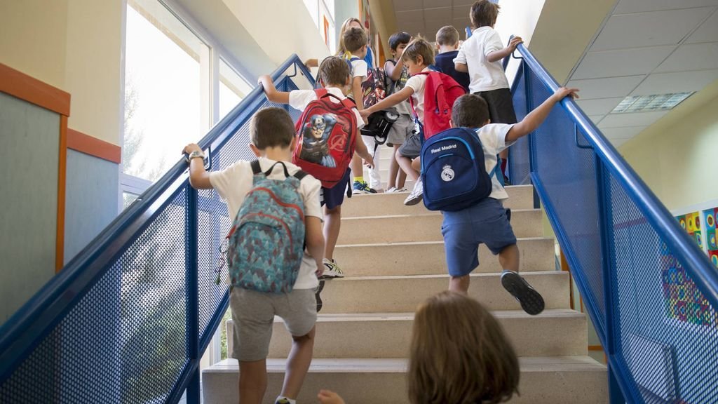 Un grupo de niños sube las escaleras de un colegio para acceder a las aulas.