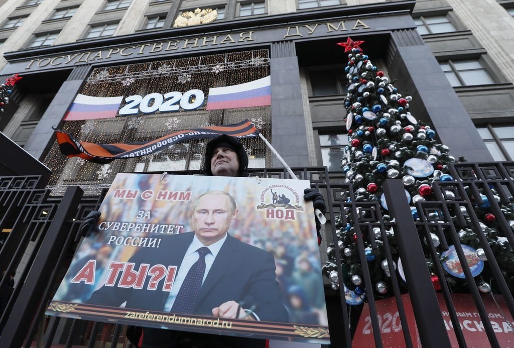 Mientras la Duma aprobaba las reformas, un simpatizante mantenía en el exterior un retrato de Putin.