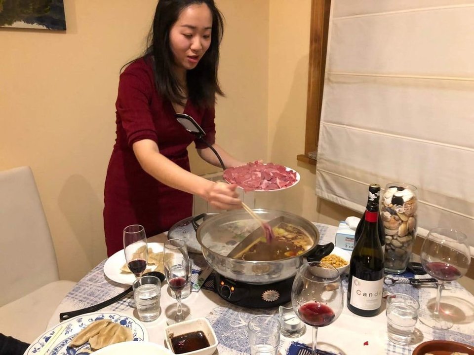 Yanqi Song echando carne de ternera en el hot pot, mientras sus invitados preparan las empanadillas chinas.
