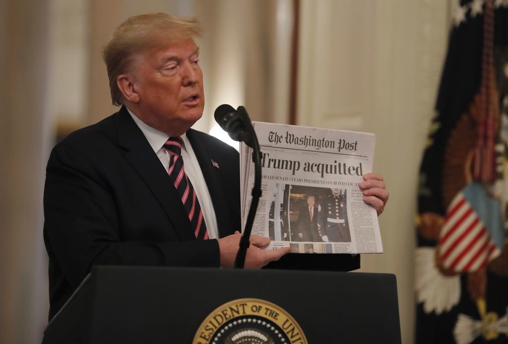El presidente de los EEUU, Donald Trump, muestra la portada de un diario que anuncia el fin del juicio político.