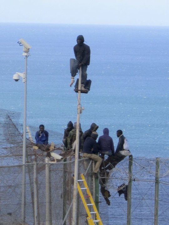 Inmigrantes encaramados a la valla de Melilla en 2014.