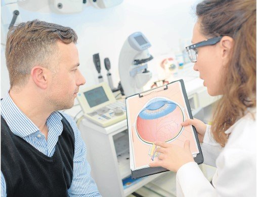 Una oftalmólga explica a un paciente mediante un gráfico en qué consiste la enfermedad.