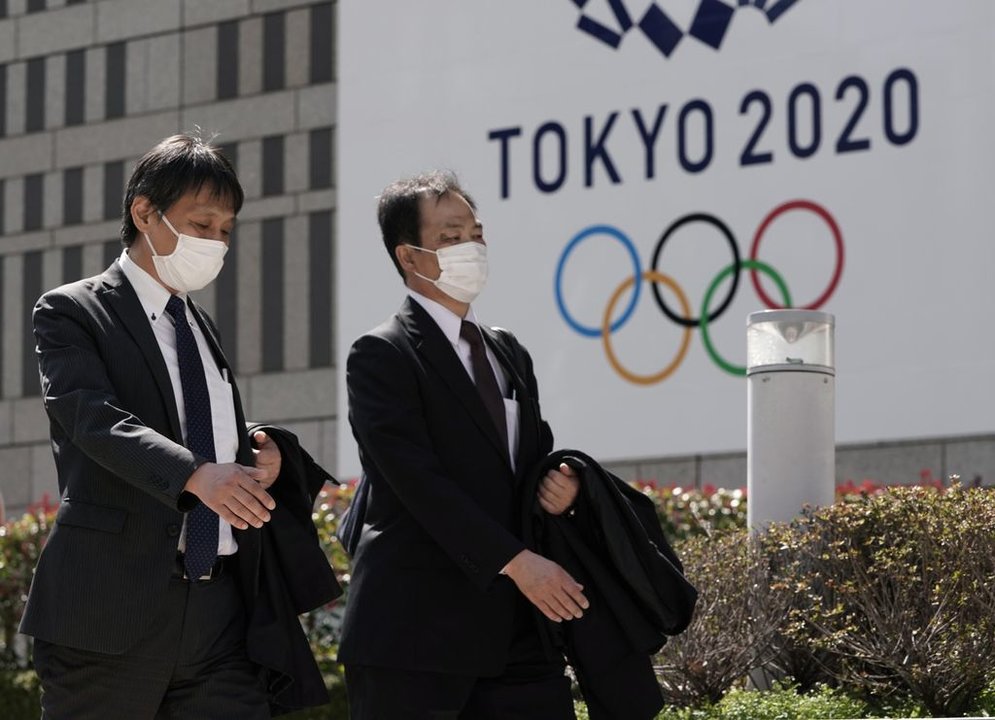 Dos oficinistas pasean, ayer, en Tokio ante un cartel de los Juegos Olímpicos del próximo verano.