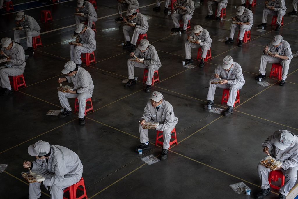 Trabajadores de una fábrica de Wuhan, que reanudó la actividad, en un sitio habilitado para comer.