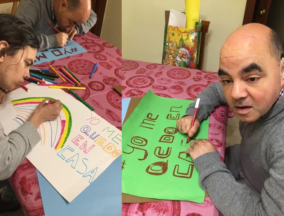 Dos personas que residen en la vivienda tutelada de Aspanaex en Vigo dibujan carteles de concienciación contra el coronavirus.