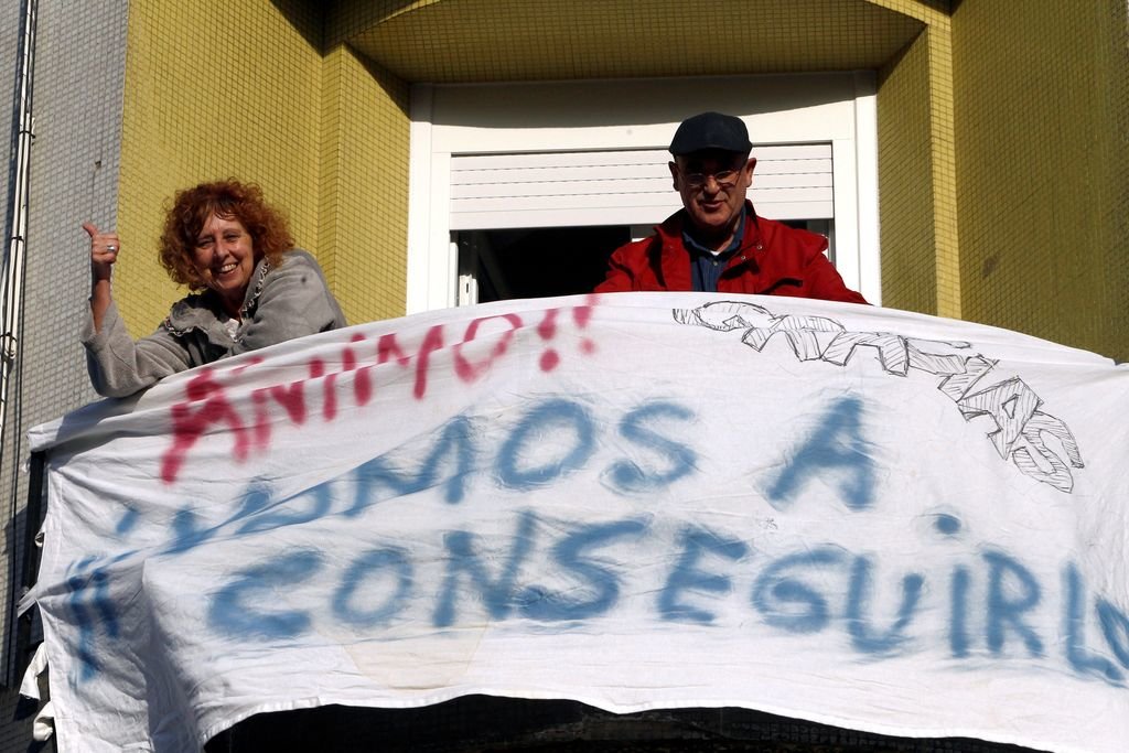 Una pareja exhibe en Narón una pancarta en un balcón animando a la ciudadanía.