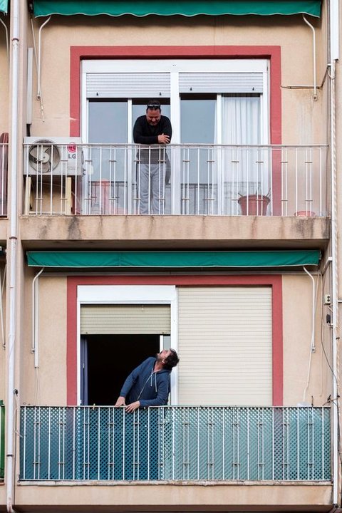 Dos hombres charlan de balcón a balcón, confinados en sus viviendas.