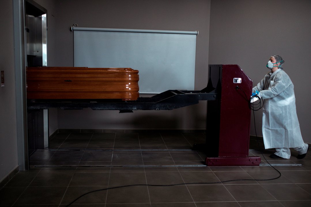 Una operaria transporta un ataúd con un fallecido por coronavirus para proceder a su incineración en el interior de la capilla del crematorio-tanatorio As Burgas 2