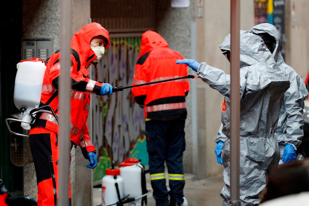 Un bombero de Barcelona desinfecta a un compañero tras salir de la residencia de religiosas
