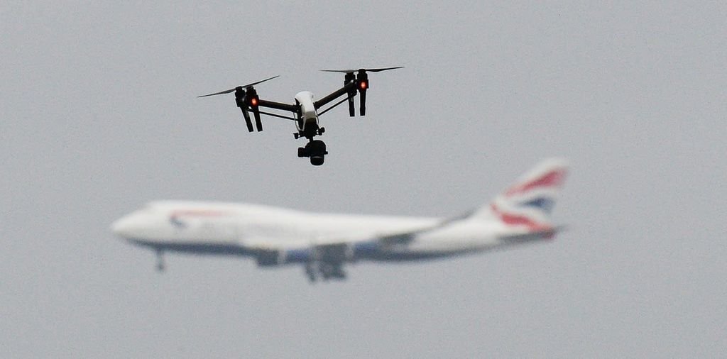 Vuelo de un dron en las inmediaciones de un aeropuerto, con un avión al fondo.