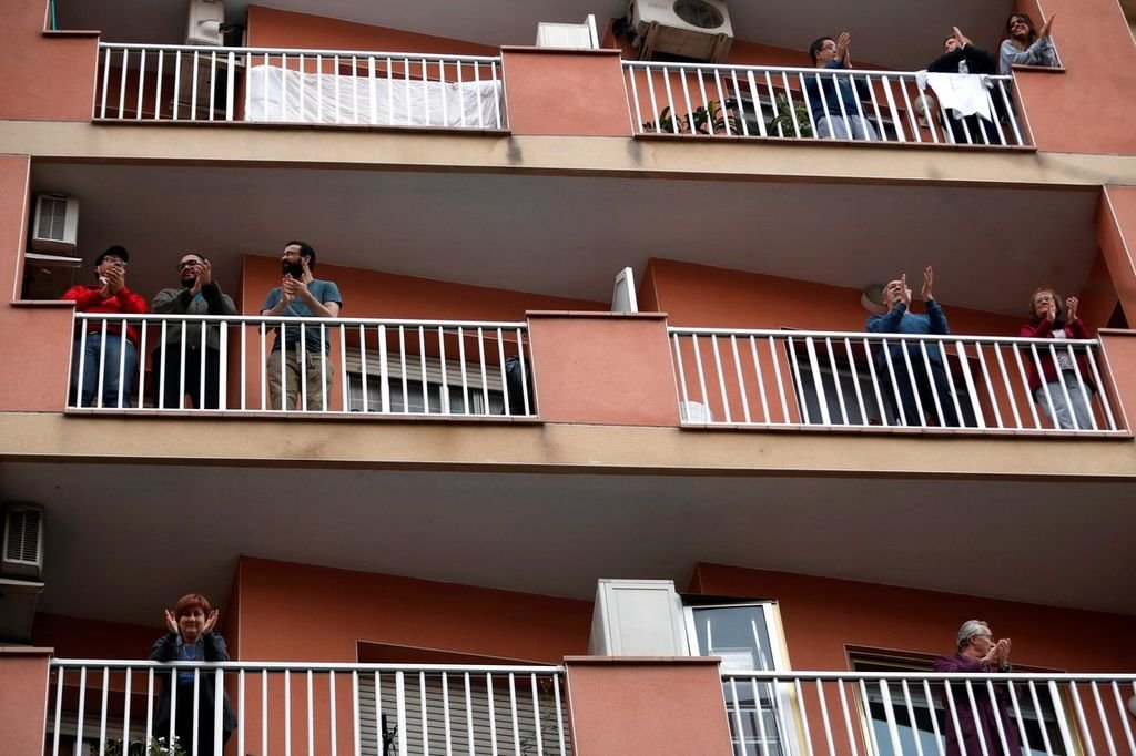 Varios personas salen a aplaudir desde sus pisos en un edificio de Barcelona.