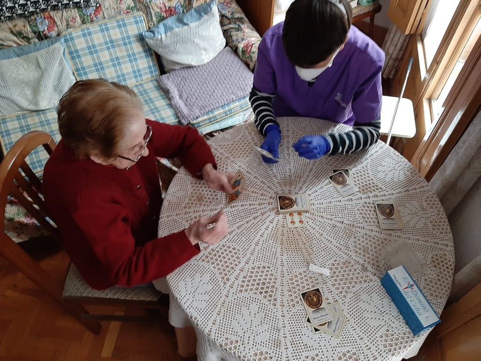 Ángela. con la auxiliar de Afaga que realiza diferentes actividades  y ejercicios de estimulación, como jugar a las cartas.