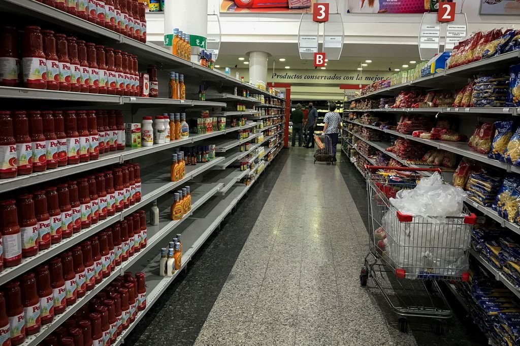 Estanterías de un supermercado de Caracas, mientras una mujer llena el carro de la compra.