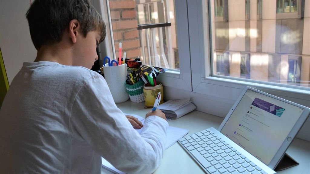 Un niño realiza los deberes en su casa mientras que realiza una consulta en su ordenador.
