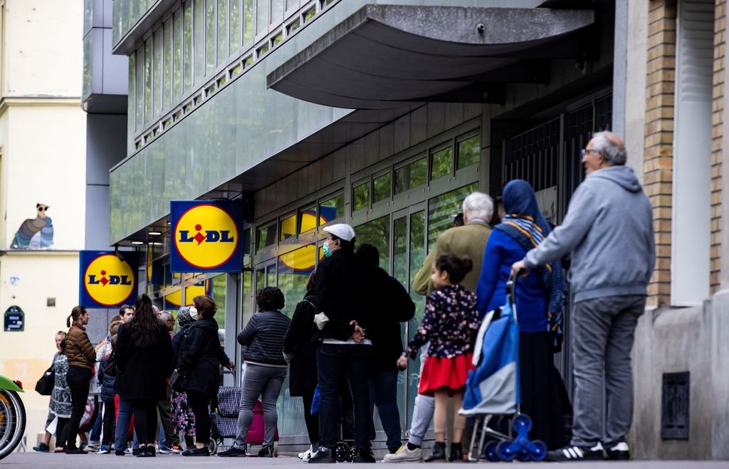 Un grupo de personas espera pacientemente su turno para entrar en un supermercado en París.