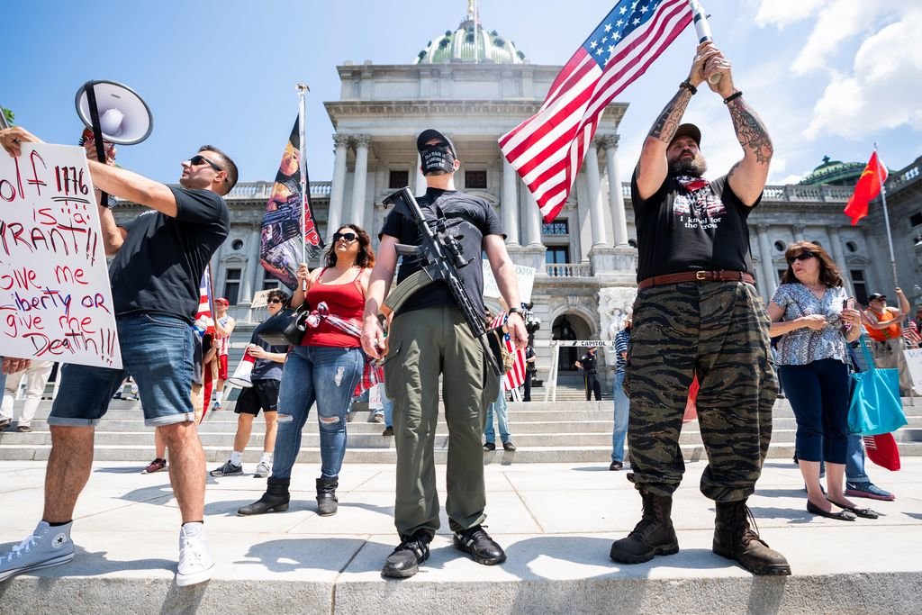 Manifestantes contra el confinamiento portan armas frente a la sede del Capitolio de Pensilvania, EEUU.