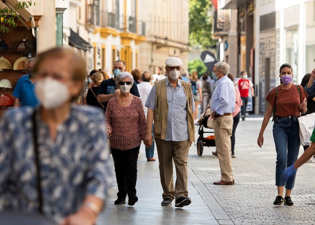 Grupos de personas con mascarrillas pasean por la calle.