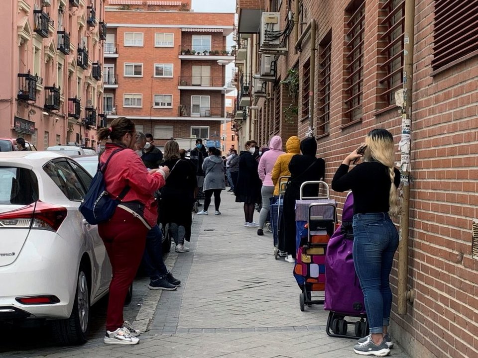 Varias personas aguardan su turno para entrar al economato de Cáritas en el distrito madrileño de Tetuán.