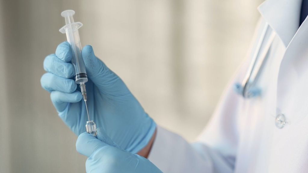 Un doctor manipula una jeringuilla antes de poner una vacuna