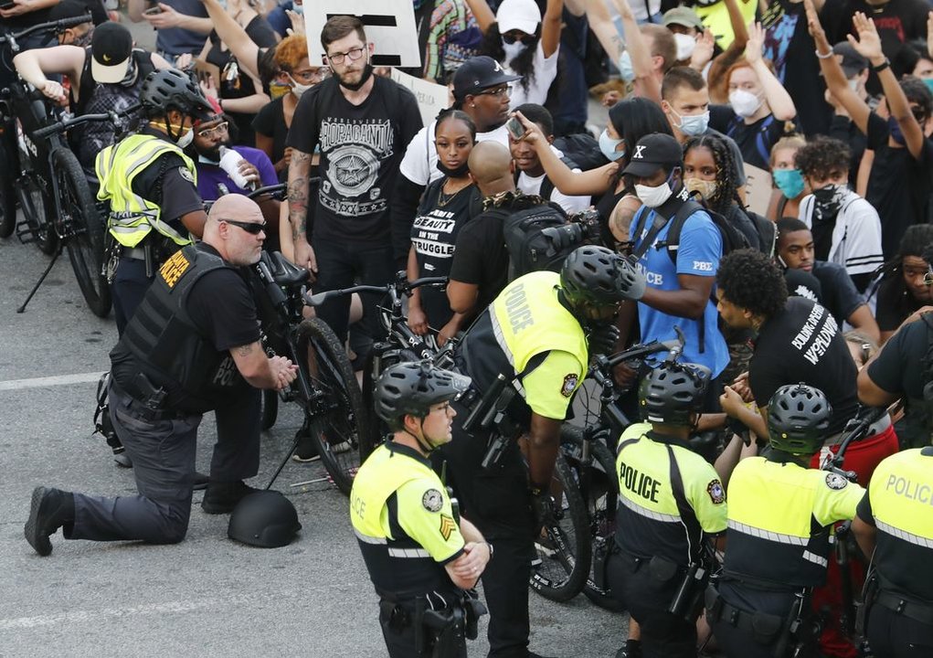 Policías se arrodillan frente a los manifestantes que protestan contra la violencia racial en Atlanta.