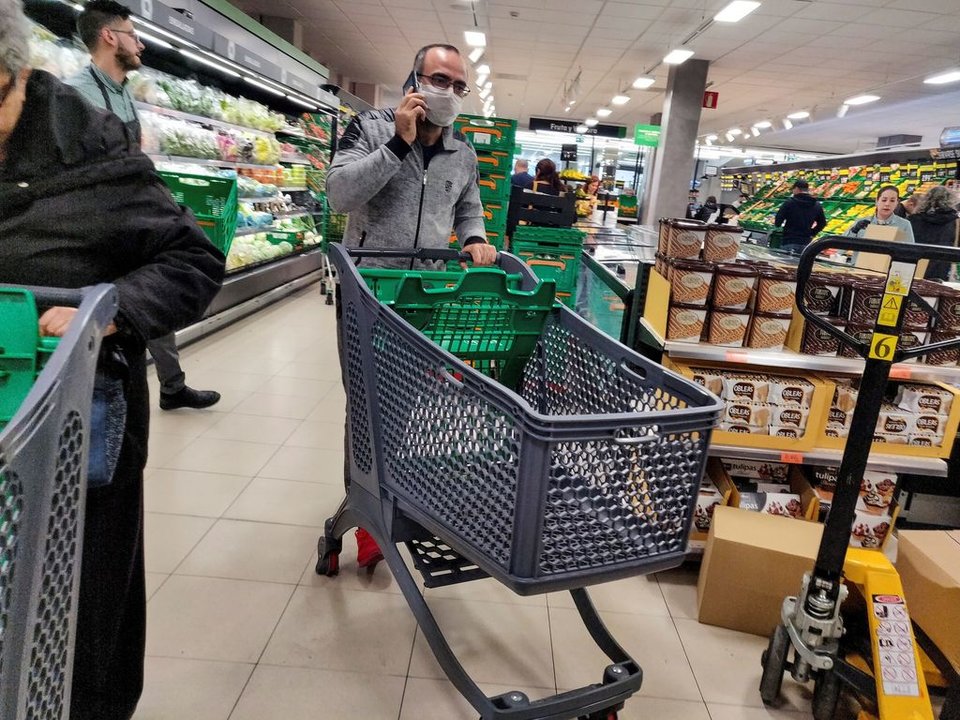 Un hombre, protegido con mascarilla, hacela compra en un supermercado.