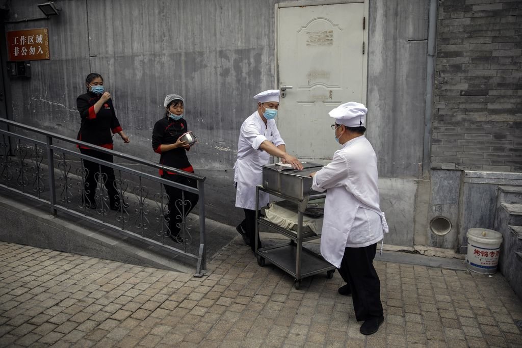 Un grupo de cocineros chinos transportan un carro de comida en una calle de Pekín.