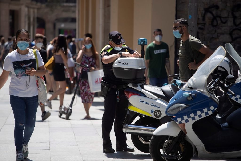 Un policía multa a un ciclista por no llevar la mascarilla en el centro de Barcelona.
