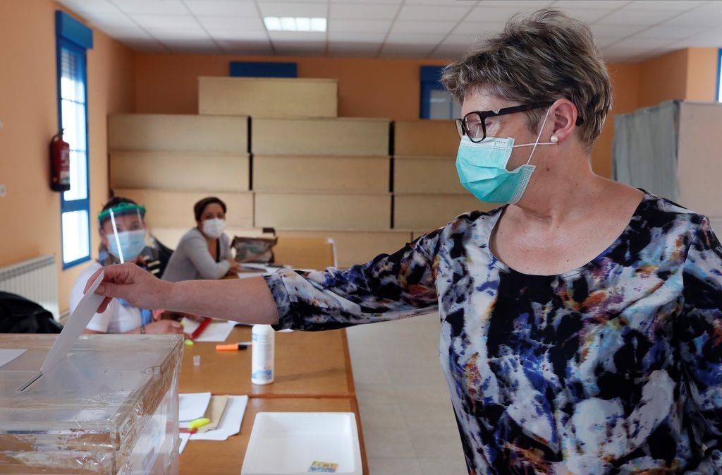 Una mujer procede a depositar su voto en urna en un colegio electoral de Foz (Lugo).
