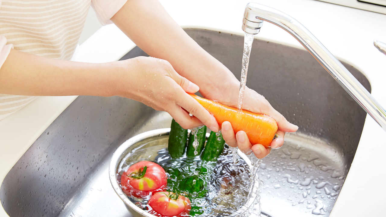 Una persona lava la fruta y verdura antes de ser consumida.