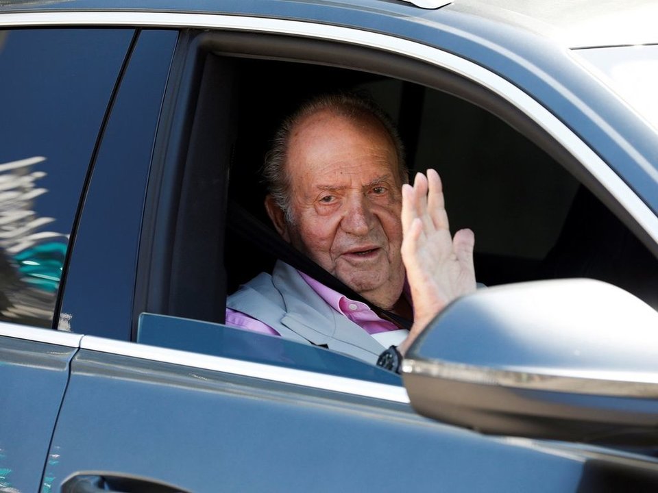 El rey Juan Carlos I saluda por la ventanilla del vehículo oficial en el que se trasladaba en España.