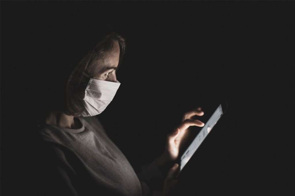 Una mujer con mascarilla busca noticias a través de su tableta electrónica.