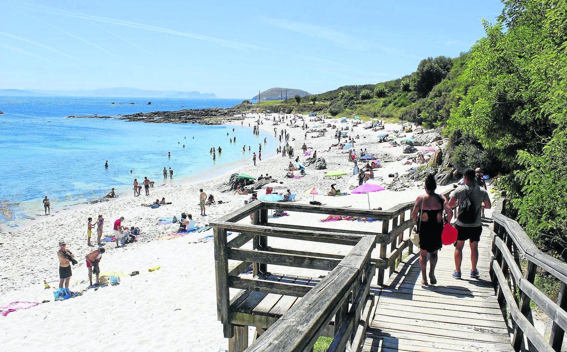 La playa de Area dos Cans se llena de turistas durante el mes de agosto, aunque manteniendo las distancias de seguridad